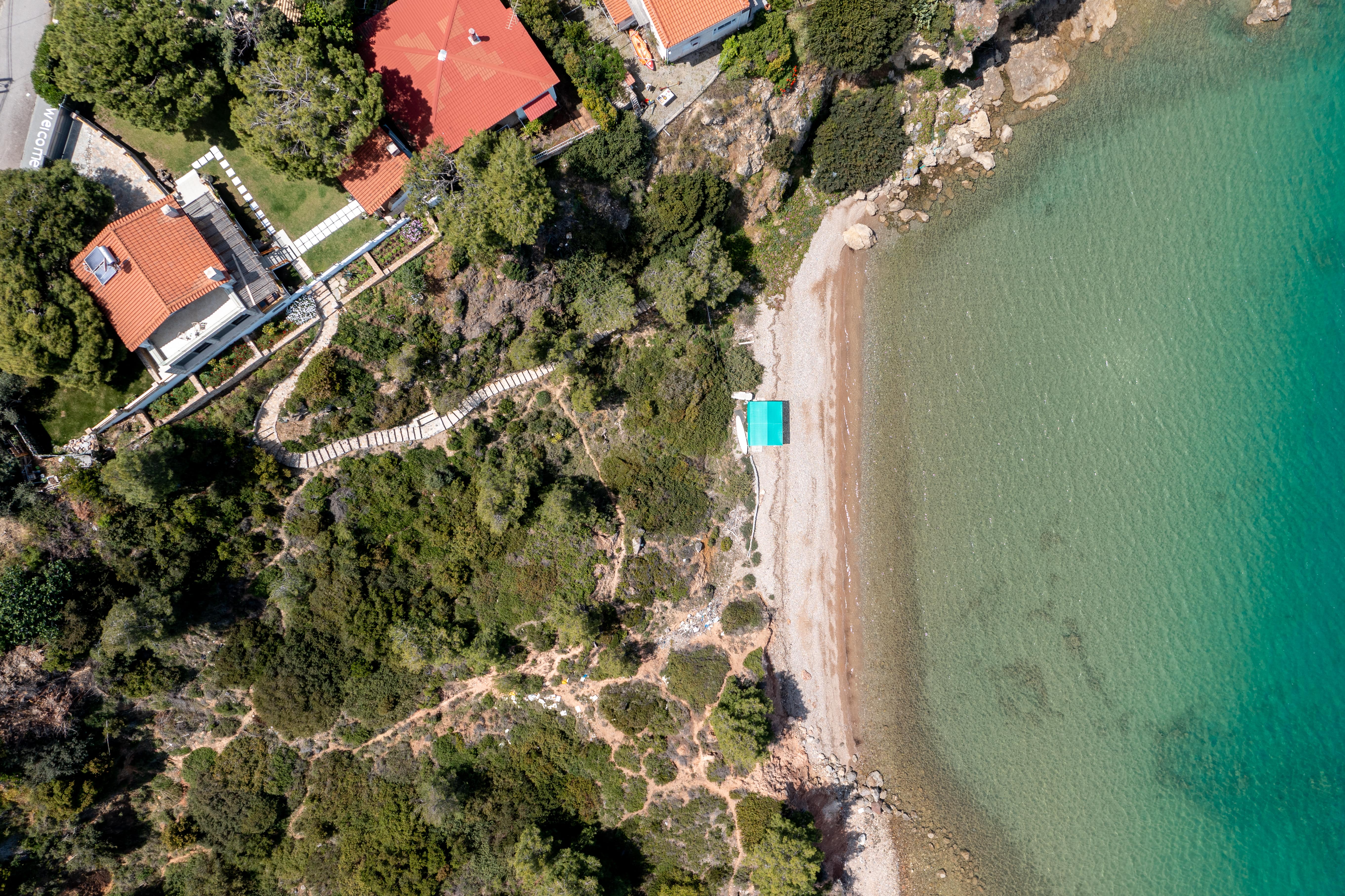 Private beach at Crystal Beach Villa with golden sand and crystal-clear water, perfect for relaxing.