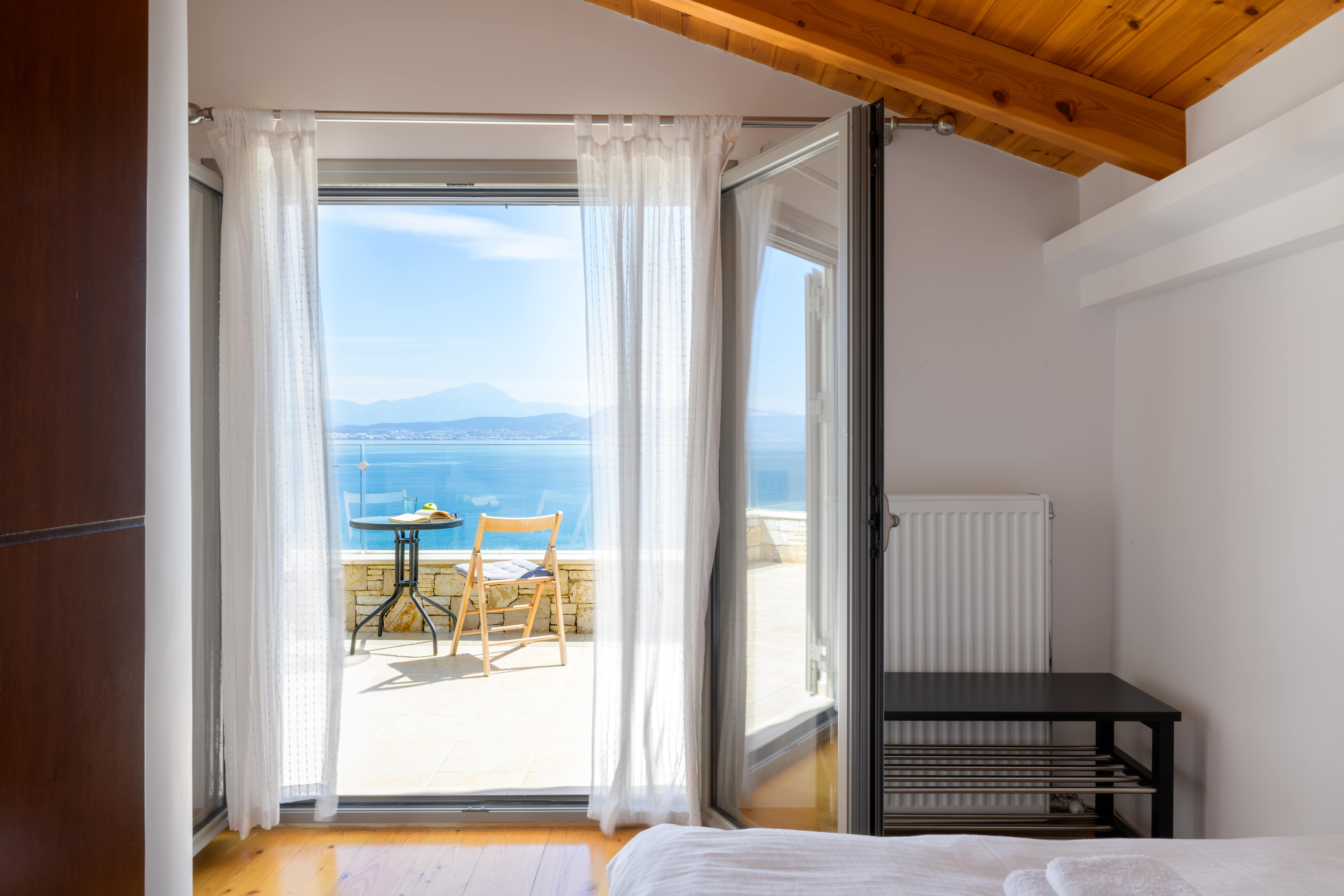Cozy balcony at Crystal Beach Villa with a table and chairs, overlooking the sparkling Aegean Sea.