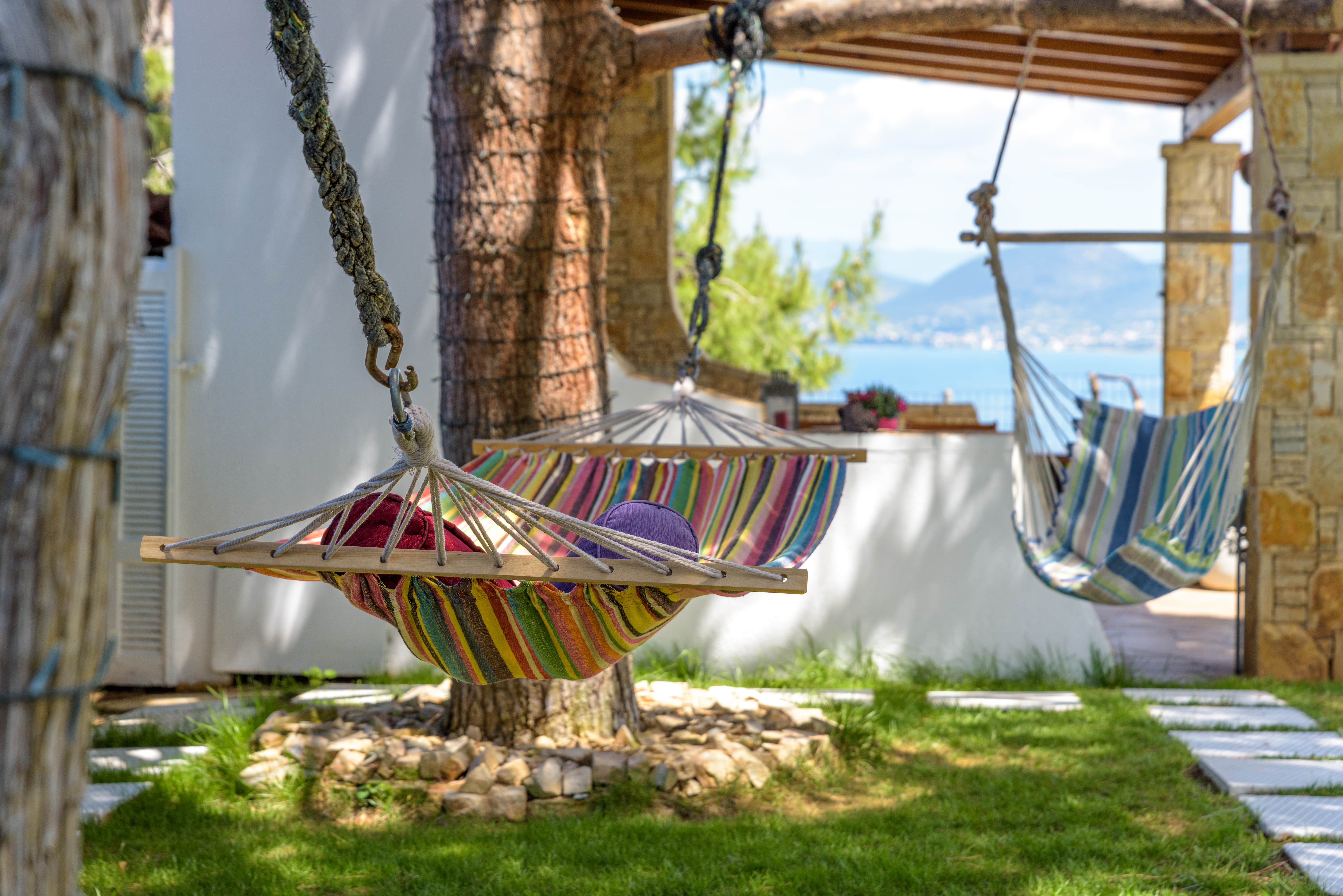 Exterior of Crystal Beach Villa with hammocks and stunning views of the Aegean Sea.